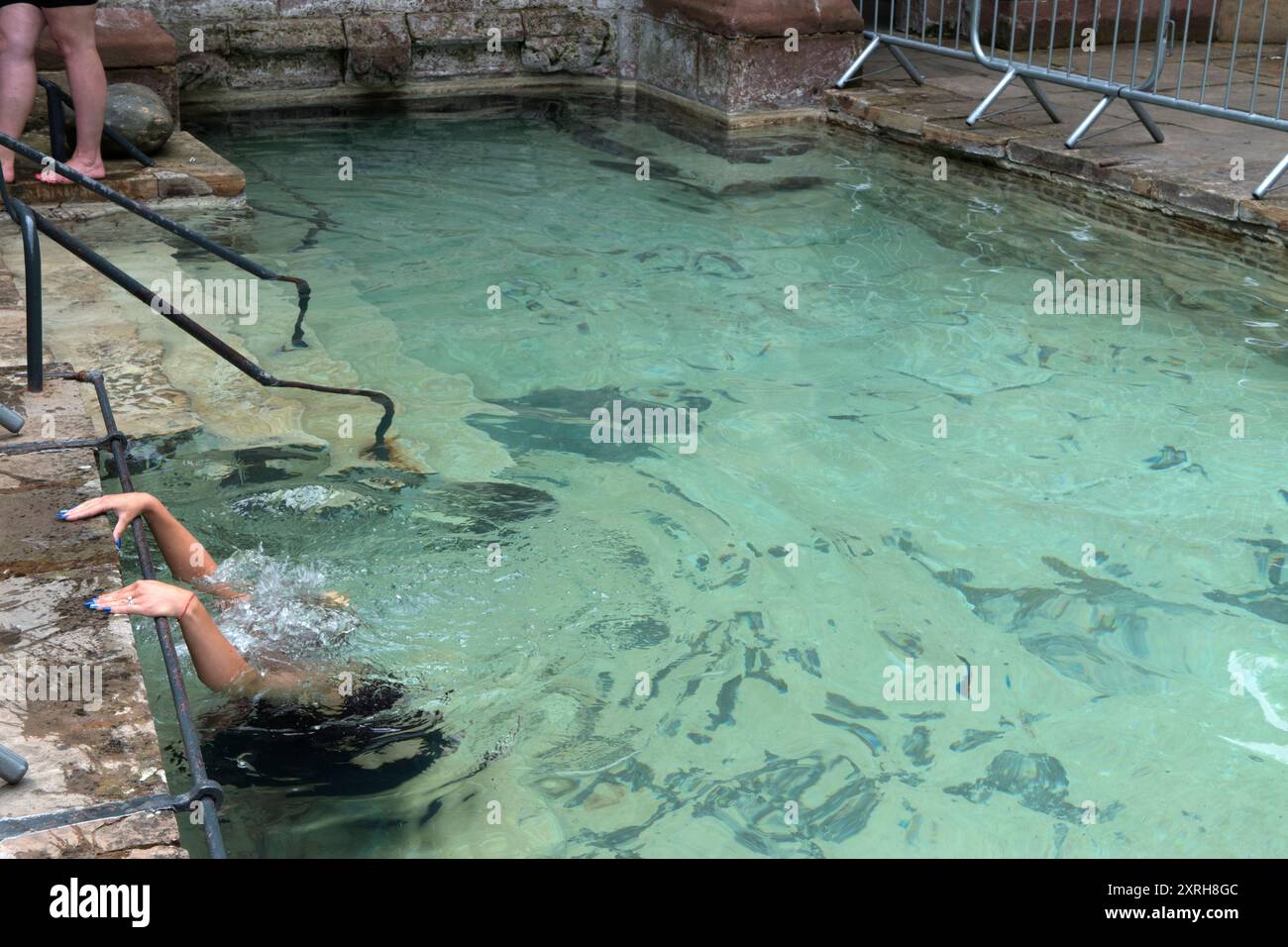 Santuario di St Winefrides e pozzo sacro. Pellegrinaggio cattolico nella festa di San Winefride 22 giugno. Nella piscina esterna una giovane donna si inginocchia su una pietra sommersa, nota come pietra di San Beuno, per tutto il tempo necessario a completare la preghiera del Rosario. Dopo aver camminato per la piscina esterna tre volte nella speranza di una cura miracolosa. Holywell, Flintshire Galles, Regno Unito anni '1990 HOMER SYKES Foto Stock