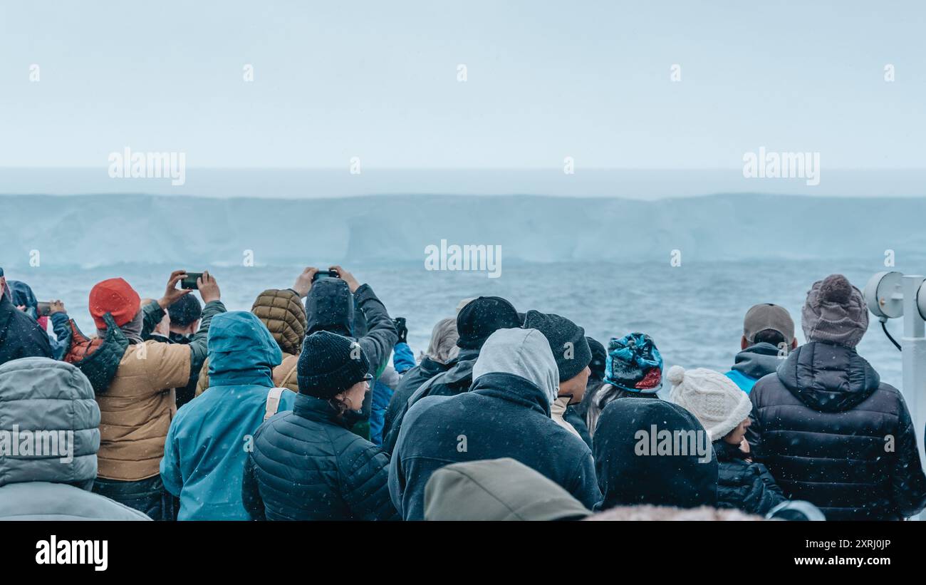 Antartide - 26 dicembre 2023 - foto di A23a Iceberg dalla nave da crociera dietro la folla che cade sulla neve. I passeggeri fotografano enormi mari ghiacciati galleggianti Foto Stock