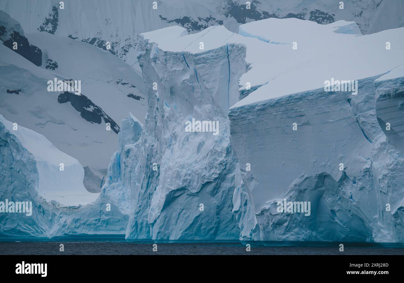 La gigantesca torre Iceberg sopra di noi, con le montagne coperte di neve sullo sfondo, primo piano, per una dettagliata fotografia del paesaggio. Natura cambiamento climatico riscaldamento globale Foto Stock