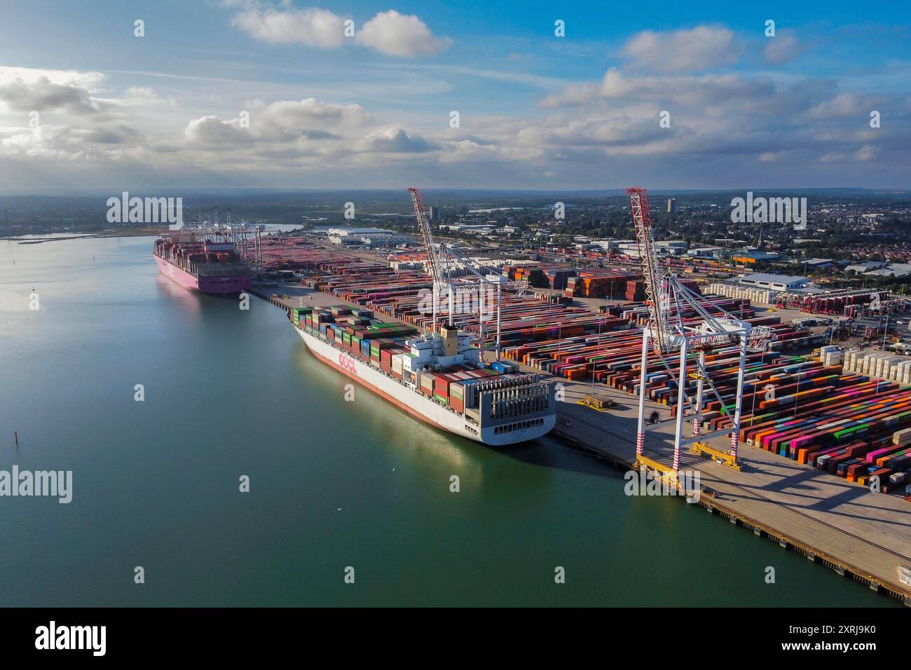 Southampton, Hampshire, Regno Unito. 10 agosto 2024. Vista aerea generale dei moli occidentali al porto di Southampton nell'Hampshire con UNA nave portacontainer e OOCL One Triumph e OOCL Seoul attraccate. Dopo il porto di Felixstowe, Southampton è il secondo terminal container più grande del Regno Unito, gestiva un traffico di 1,5 milioni di unità equivalenti (TEU). Crediti fotografici: Graham Hunt/Alamy Live News Foto Stock