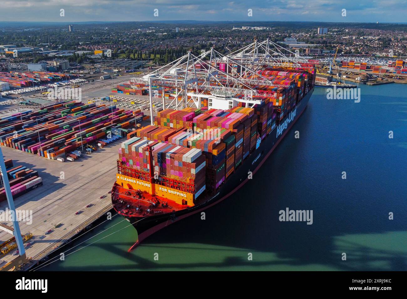 Southampton, Hampshire, Regno Unito. 10 agosto 2024. Vista aerea generale dei Western Docks al porto di Southampton, nell'Hampshire, con la nave container Hapag-Lloyd Damietta Express attraccata che porta il messaggio "Un futuro più pulito per la spedizione". Dopo il porto di Felixstowe, Southampton è il secondo terminal container più grande del Regno Unito, gestiva un traffico di 1,5 milioni di unità equivalenti (TEU). Crediti fotografici: Graham Hunt/Alamy Live News Foto Stock