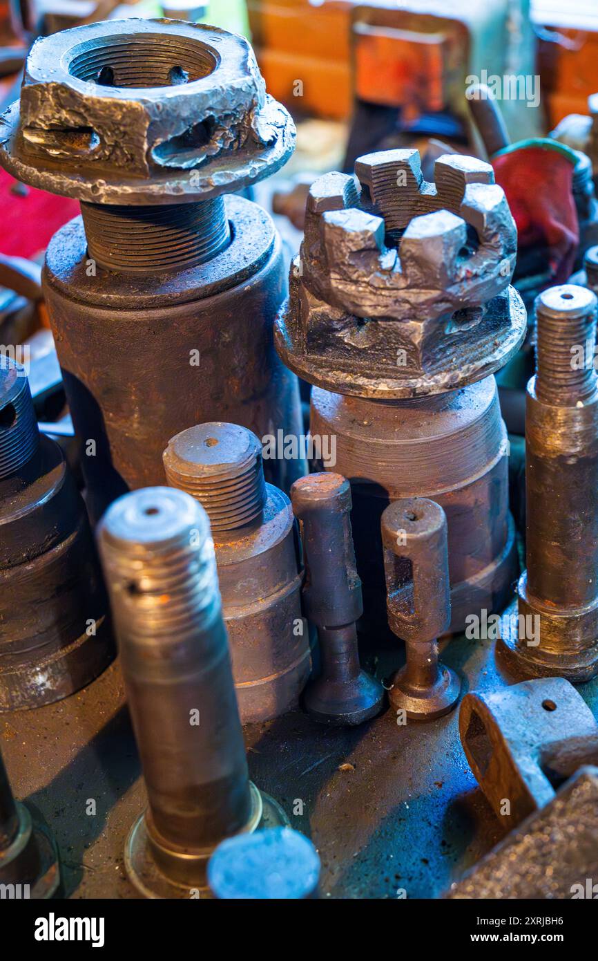 Vista dettagliata degli utensili e delle attrezzature metalliche in un'officina di lavorazione dei metalli circondata da vari materiali e macchinari Foto Stock