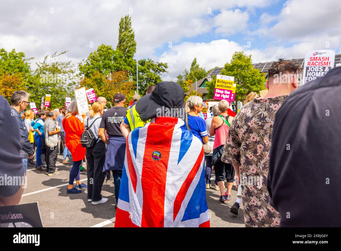 Wakefield, Regno Unito. 10 AGOSTO 2024. La persona indossa un Union Jack con un adesivo "stand up to razzism" mentre oltre un centinaio di dimostranti si sono riuniti fuori dall'hotel Cedar Court in previsione di una folla di destra a causa del ruolo degli hotel nell'ospitare i migranti. I contro dimostranti erano composti da SUTR e altri gruppi di sinistra e tenevano discorsi. La presenza della polizia era eccezionalmente elevata, con 20 furgoni e 2 veicoli corazzati "Bearcat". Non sono arrivati manifestanti appoggiati all'ala destra e il contatore demo è andato via senza problemi. Credito Milo Chandler/Alamy Live News Foto Stock