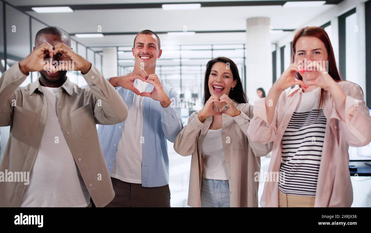 Dipendenti aziendali felici che creano cuori con le mani. Comunità sul luogo di lavoro Foto Stock