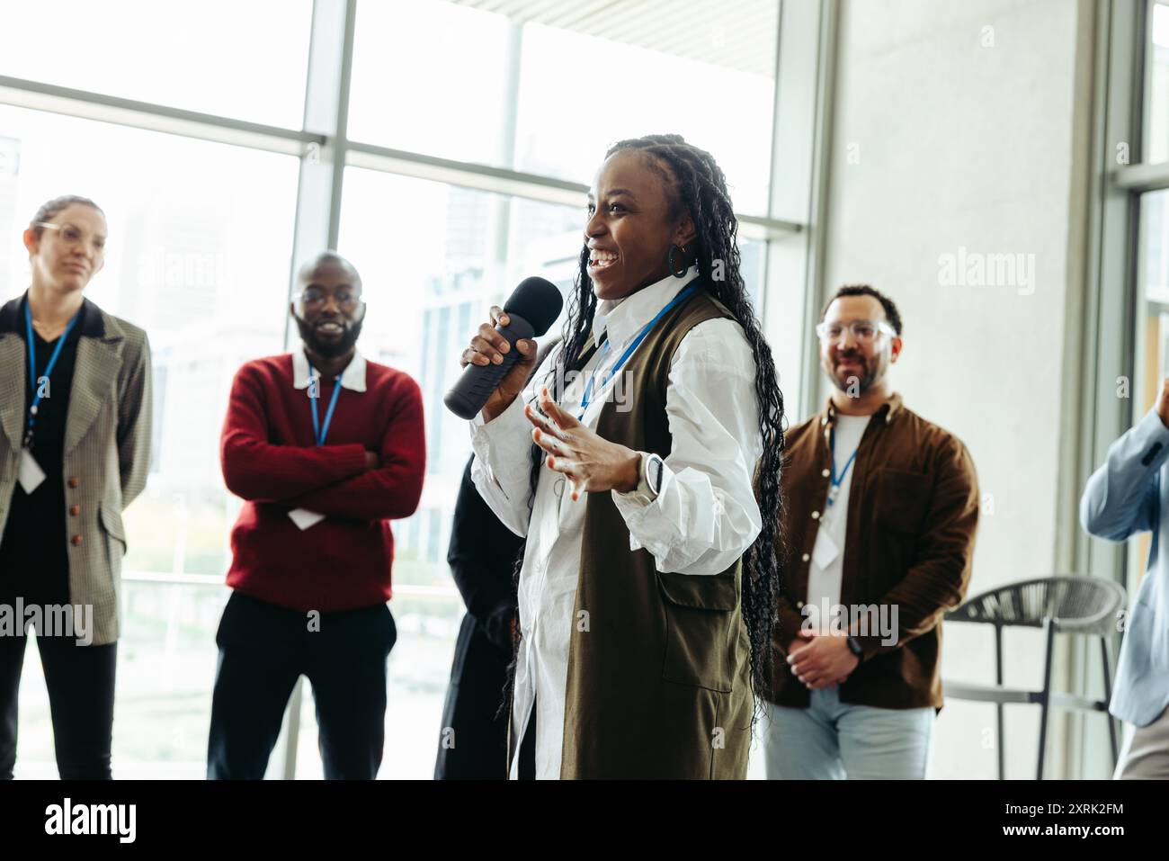 Donna sicura di sé che parla a una conferenza con i colleghi in un ufficio moderno. Presentazione di idee a colleghi impegnati e diversi. Foto Stock