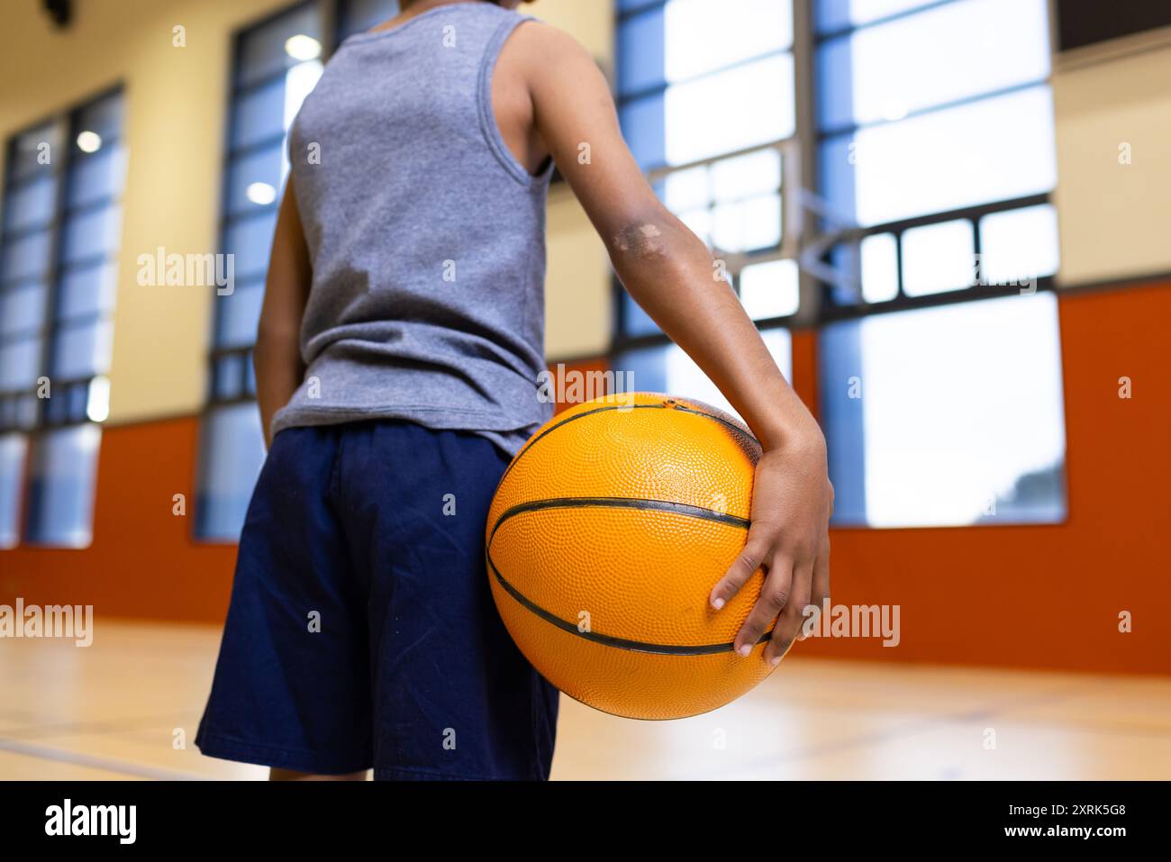 Tiene il basket, ragazzo in piedi nella palestra scolastica, pronto per l'allenamento Foto Stock