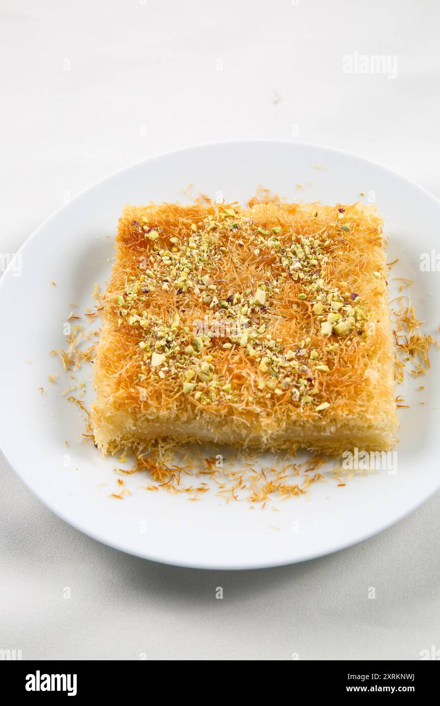 Dolci tradizionali arabi fatti in casa kunafa o noci knafeh sulla parte superiore, formaggio e sciroppo di zucchero, sul vassoio Foto Stock