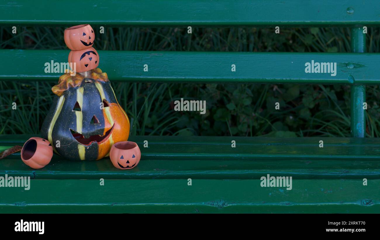 Un gruppo di zucche di buon umore su una panchina verde. Copia spazio. Halloween. Foto Stock
