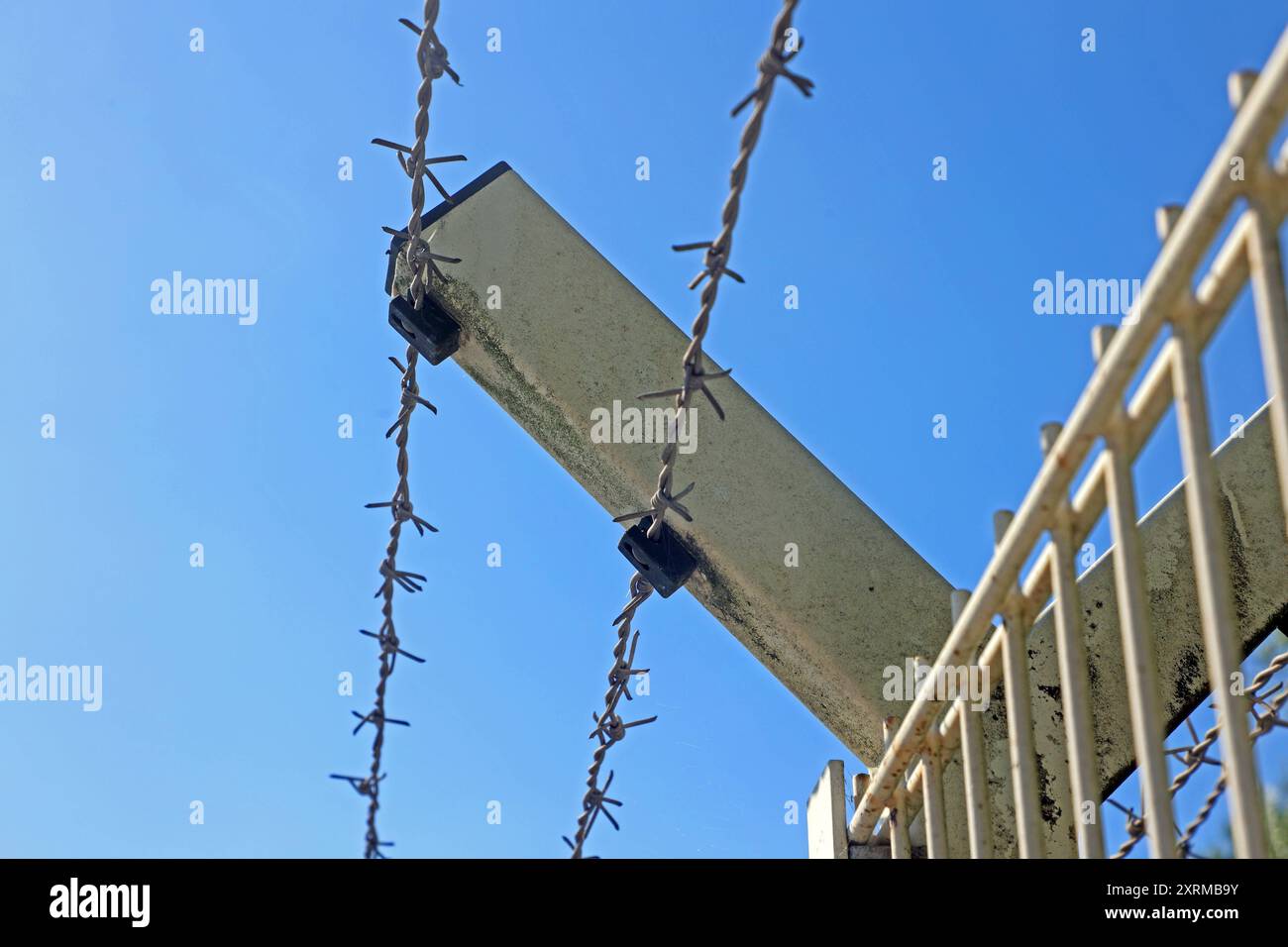 Zäune aus massiven materiale Ein unbeschichteter Stahlmattenzaun mit Stacheldraht am oberen Ende als Schutz an einem Gewerbegebiet *** recinzioni in materiale solido recinzione in rete di acciaio non rivestito con filo spinato nella parte superiore come protezione in una zona industriale Foto Stock