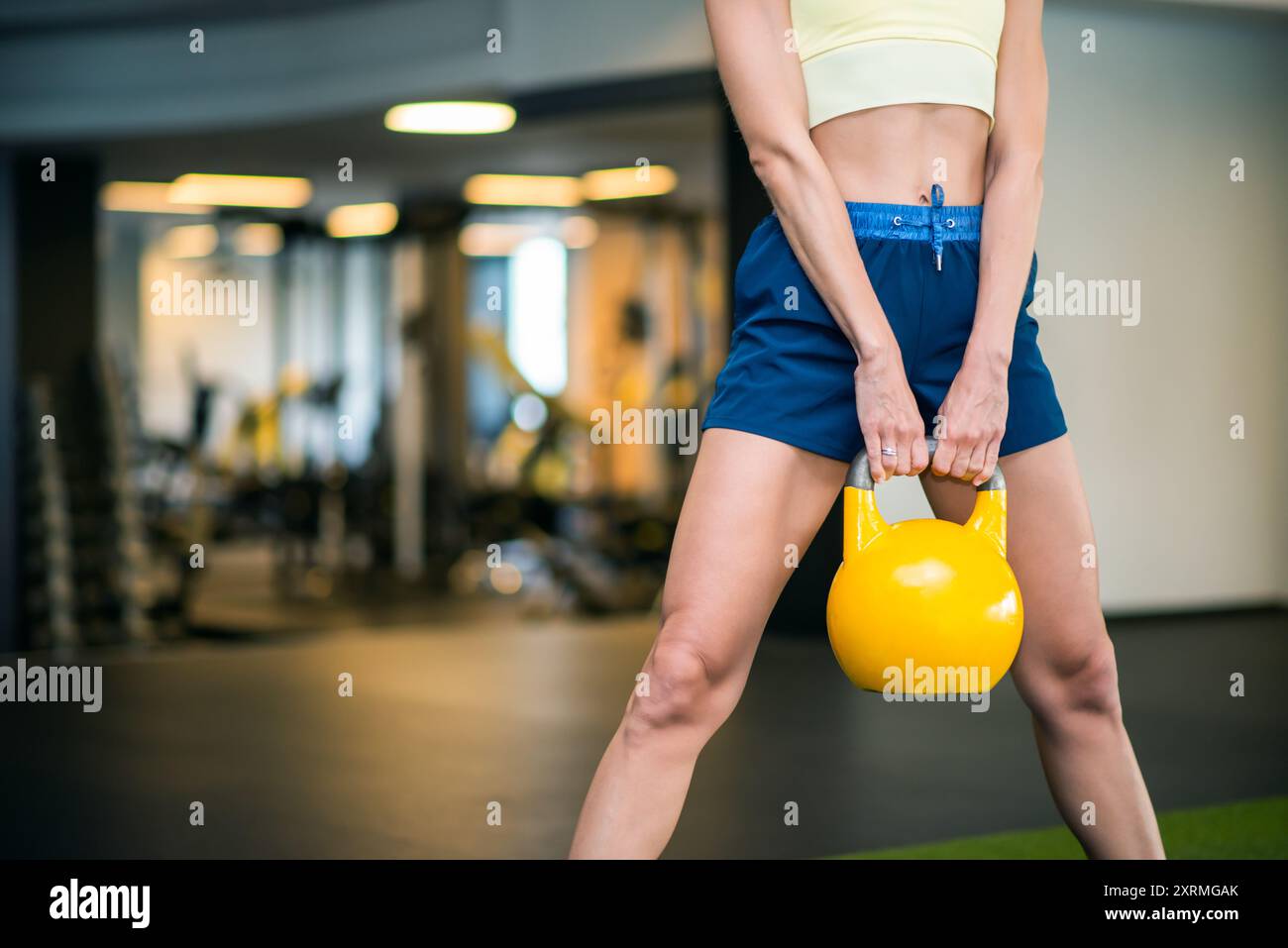 Donna che tiene una palla di kettlebell in palestra, senza volto Foto Stock