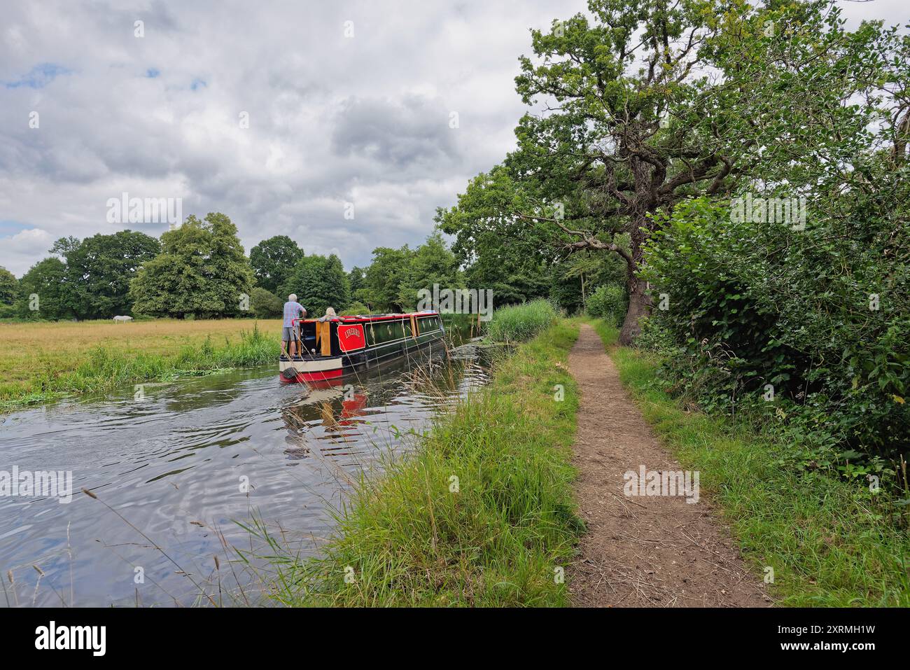 Una barca stretta che naviga sul canale di navigazione del fiume Wey vicino a Byfleet, in una giornata estiva Surrey Inghilterra Regno Unito Foto Stock