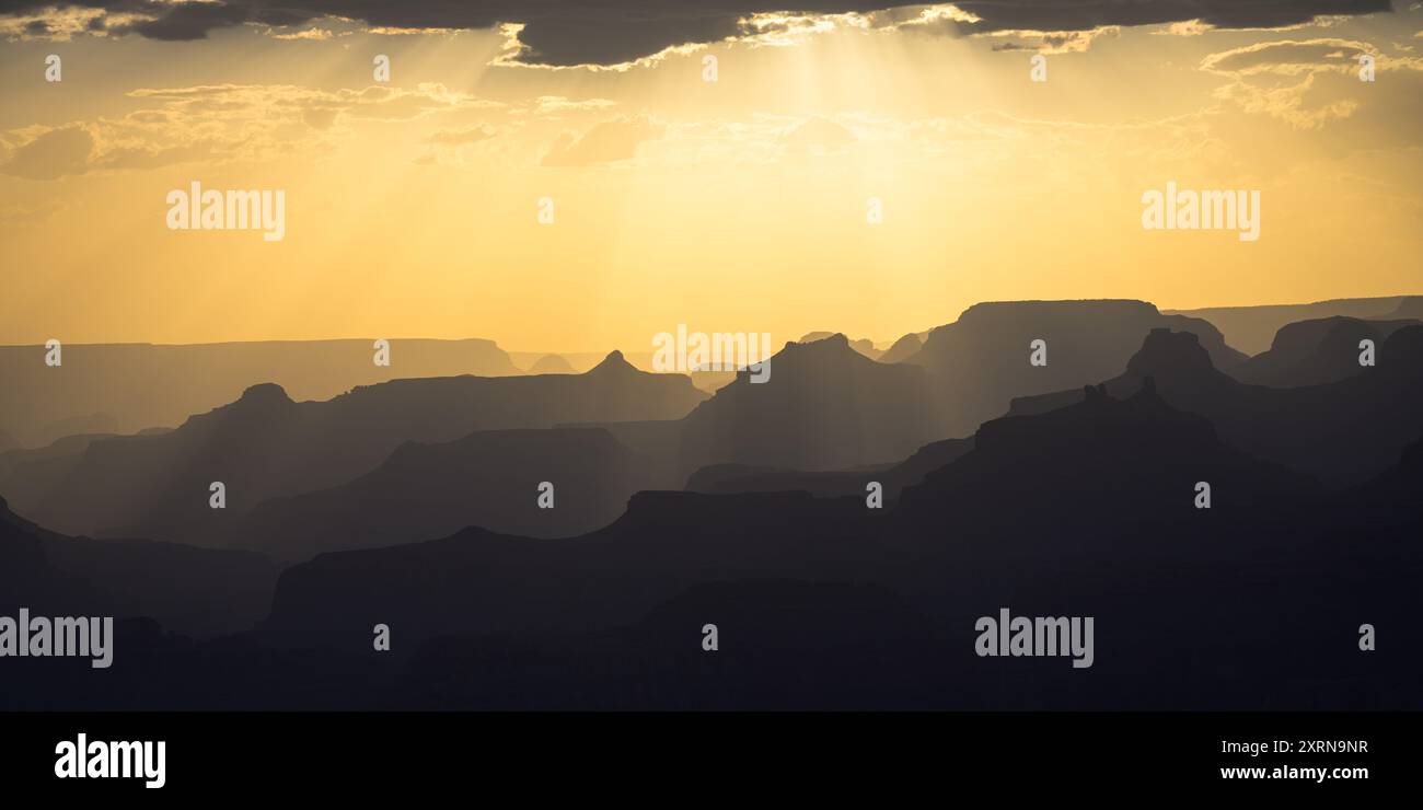 La polvere nell'aria sopra le creste del Grand Canyon mette in luce i raggi del sole in colori caldi Foto Stock