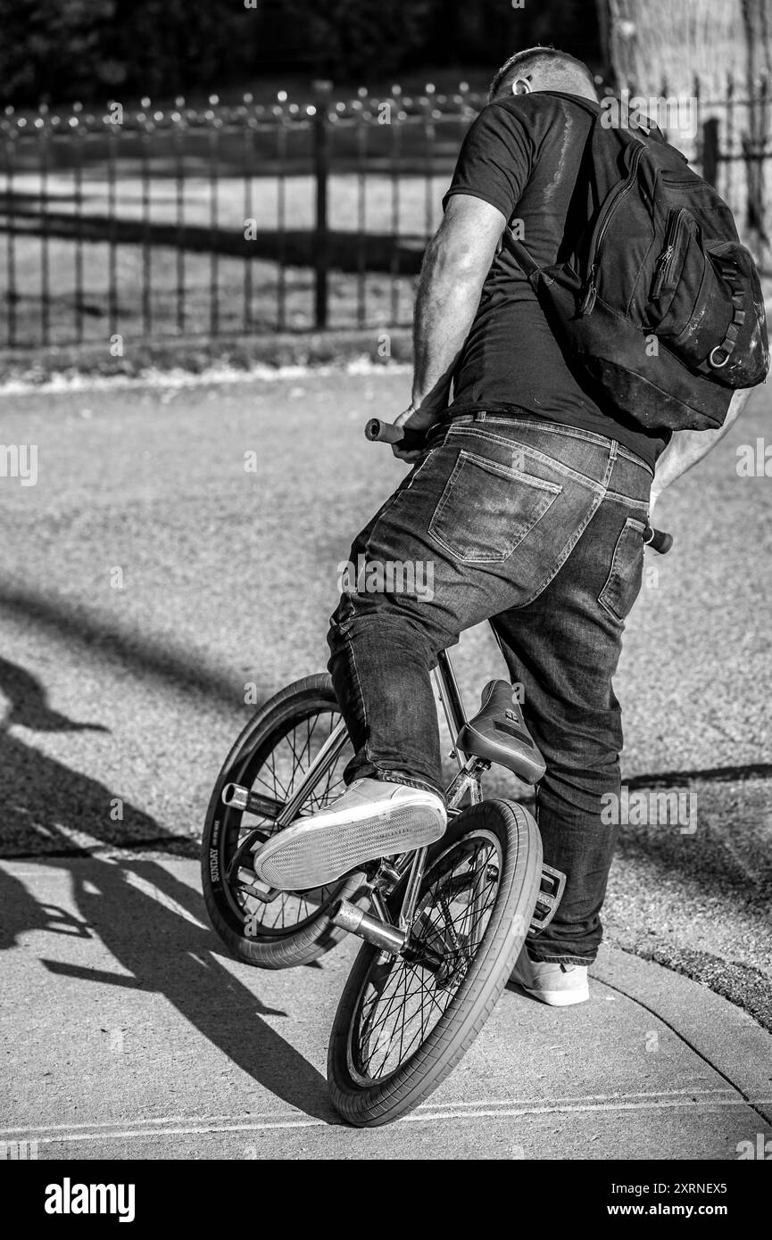 Questo grande uomo ha fatto tutto quello che poteva fare per guidare questa piccola bici. Ma non molta fortuna. Era per gran parte di una cosa, non abbastanza dell'altra. Il sedile. Foto Stock