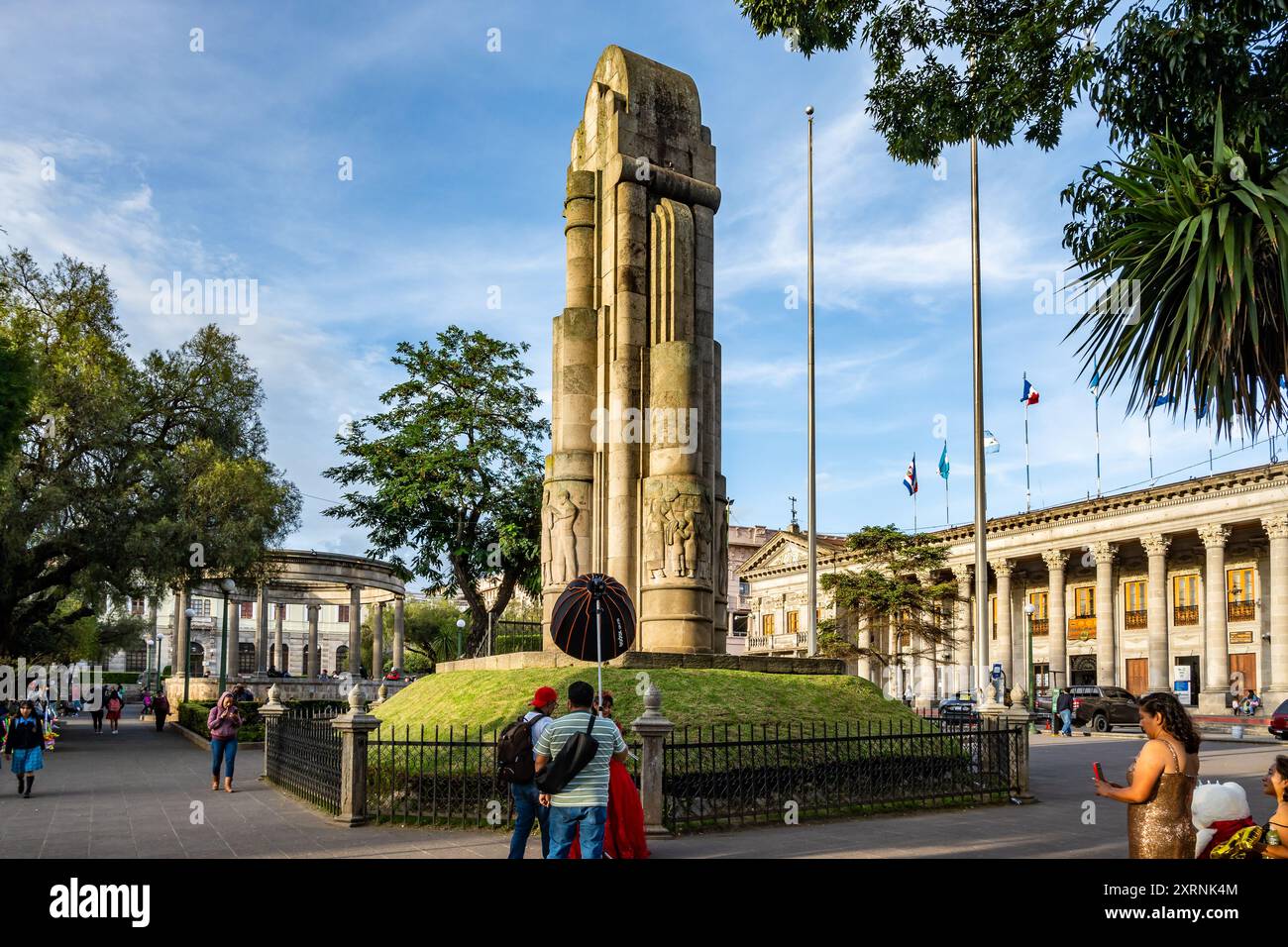 Fotografo che scatta foto di una donna davanti a un monumento al Parque Centro América. Quetzaltenango, Guatemala. Foto Stock