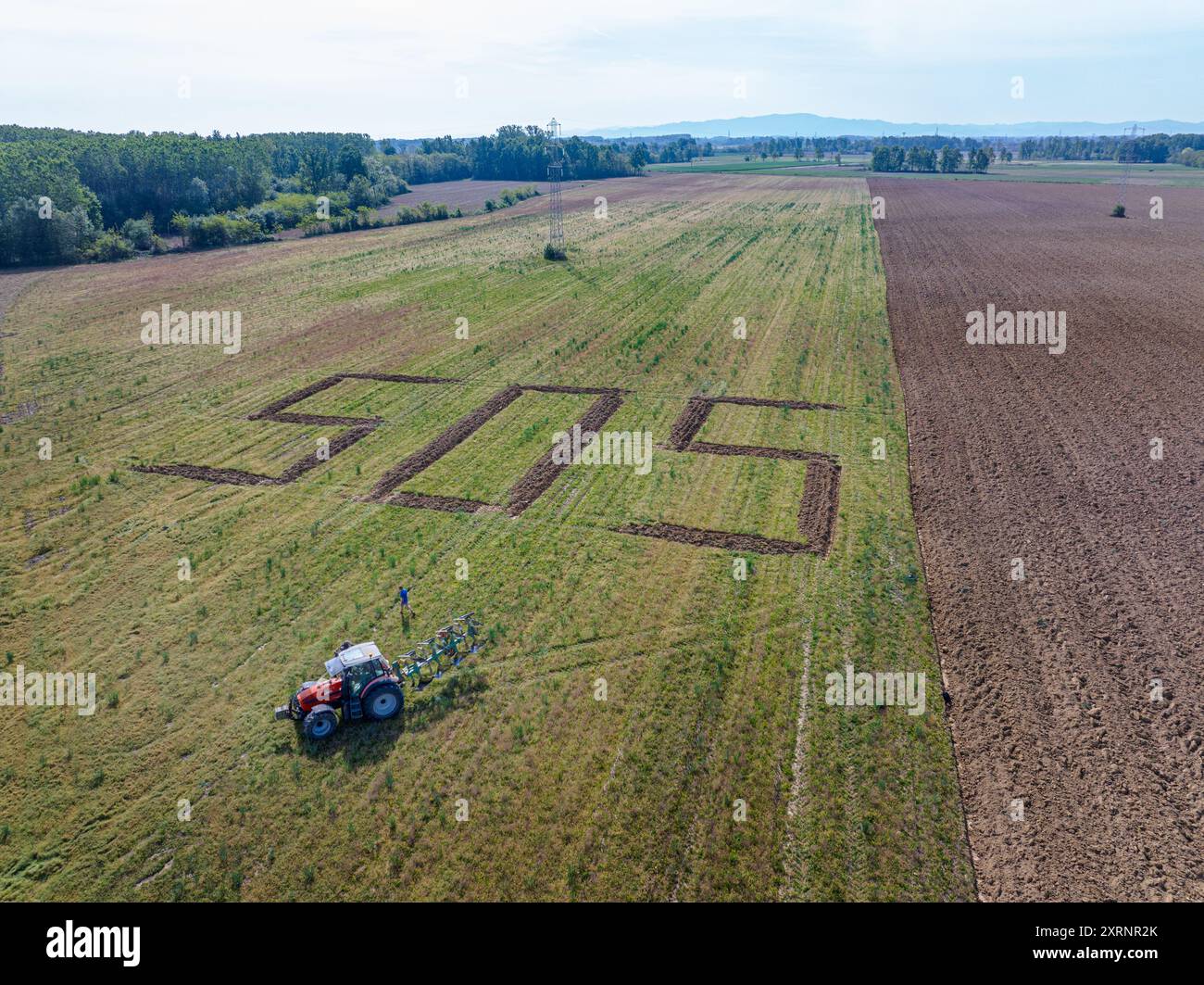 Un SOS gigante, un richiamo simbolico contro l'uso eccessivo del suolo, scritto nel terreno da un trattore. Foto Stock