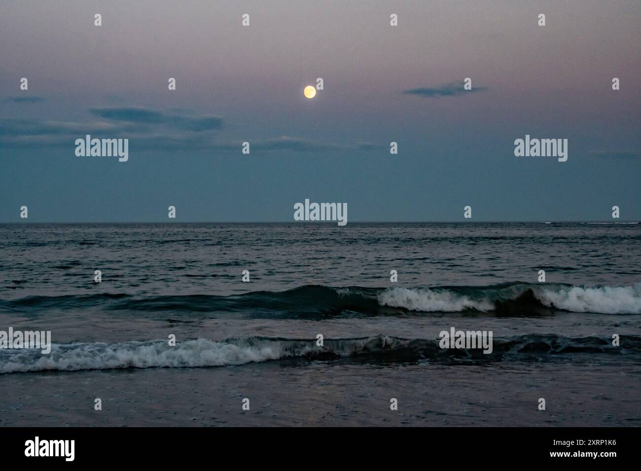 La luna piena sorge sull'Oceano Atlantico Foto Stock