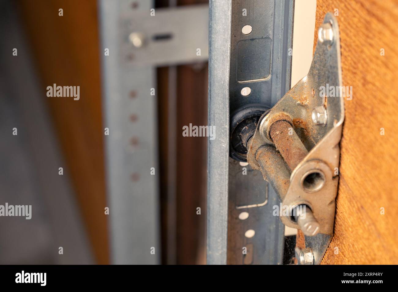 Primo piano della cerniera della porta del garage e del rullo sulla porta di legno, messa a fuoco selettiva. Foto Stock