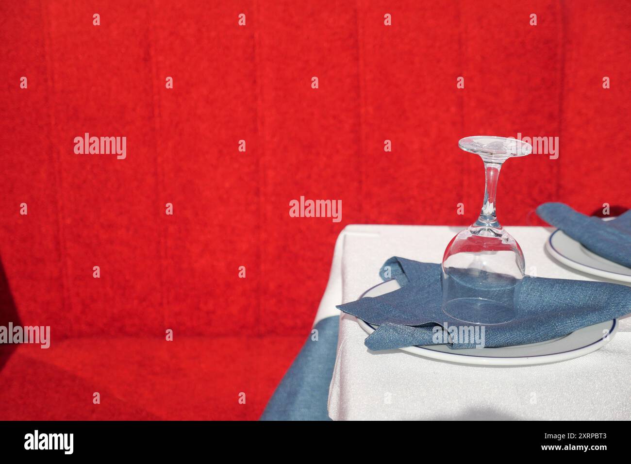 Un elegante ambiente da pranzo con sfondo rosso e un array di stoviglie di qualità Foto Stock