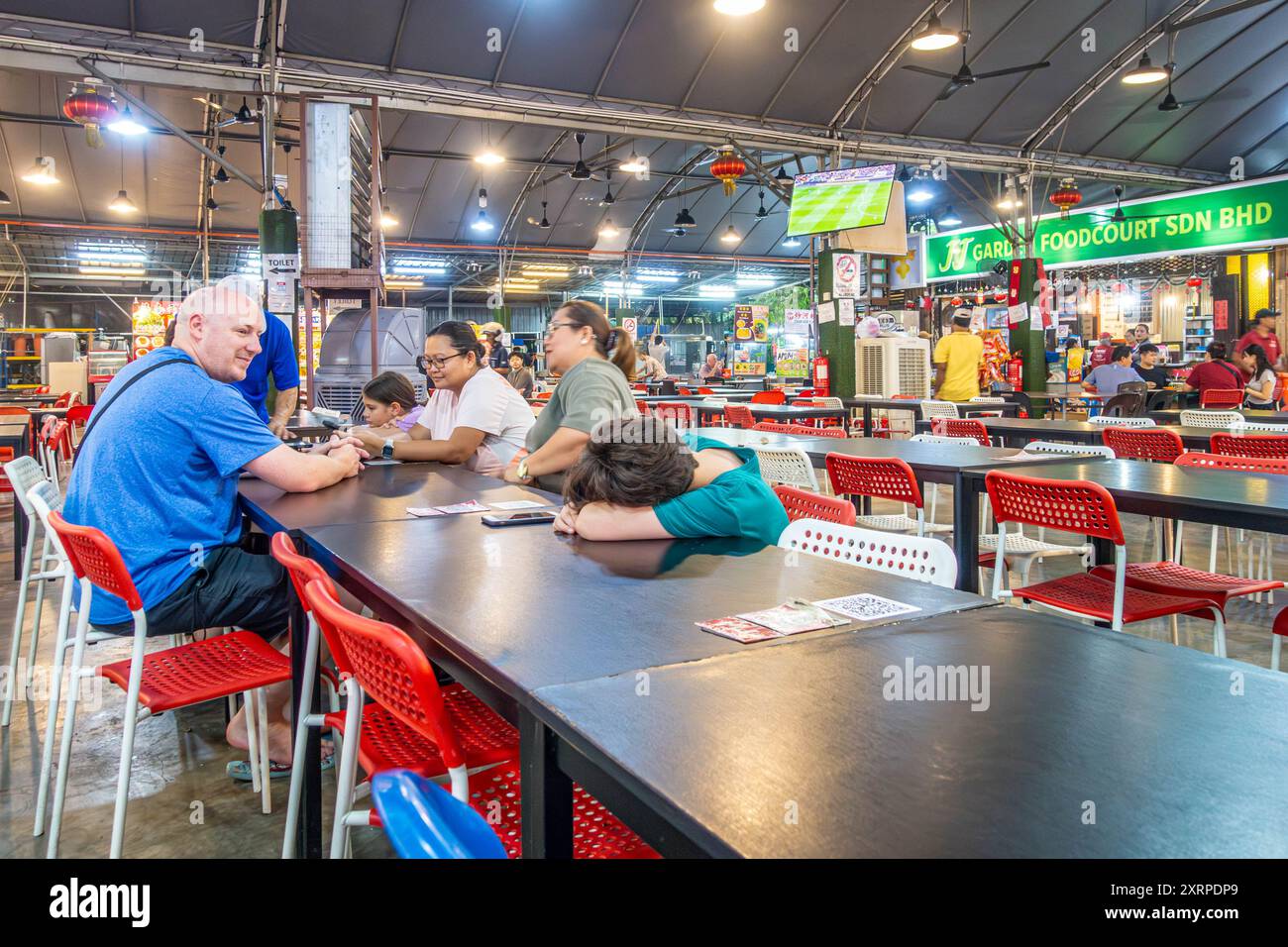 Una famiglia seduta a un tavolo pronta a mangiare al food Court JJ Garden di Tanjung Bungah, Penang, Malesia Foto Stock
