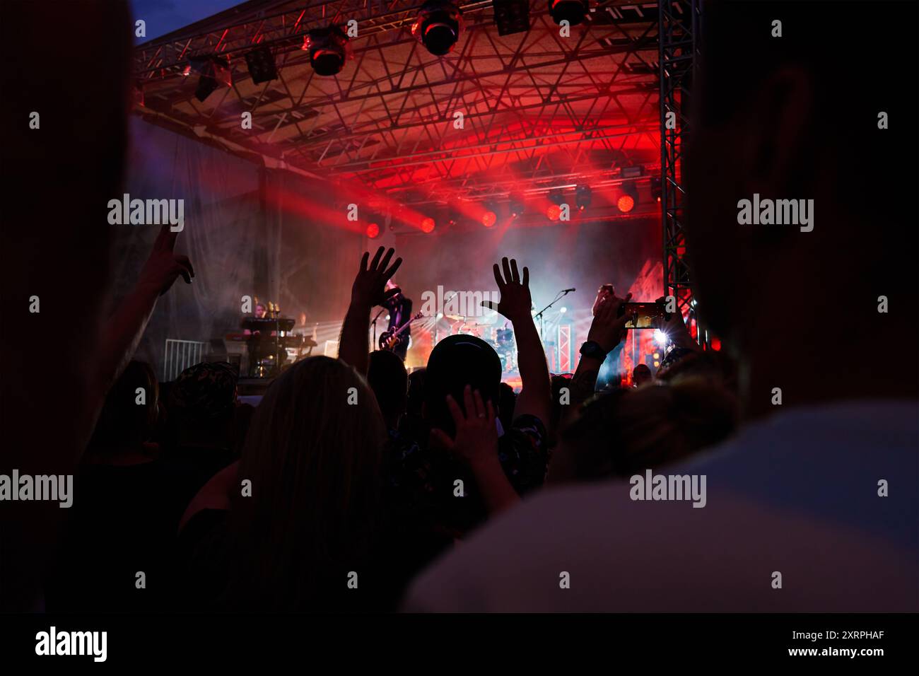 Sagome della folla al concerto di fronte al palco con luci spot luminose. Le persone amano la musica dal vivo durante l'esibizione della band. Sala concerti con musical Foto Stock