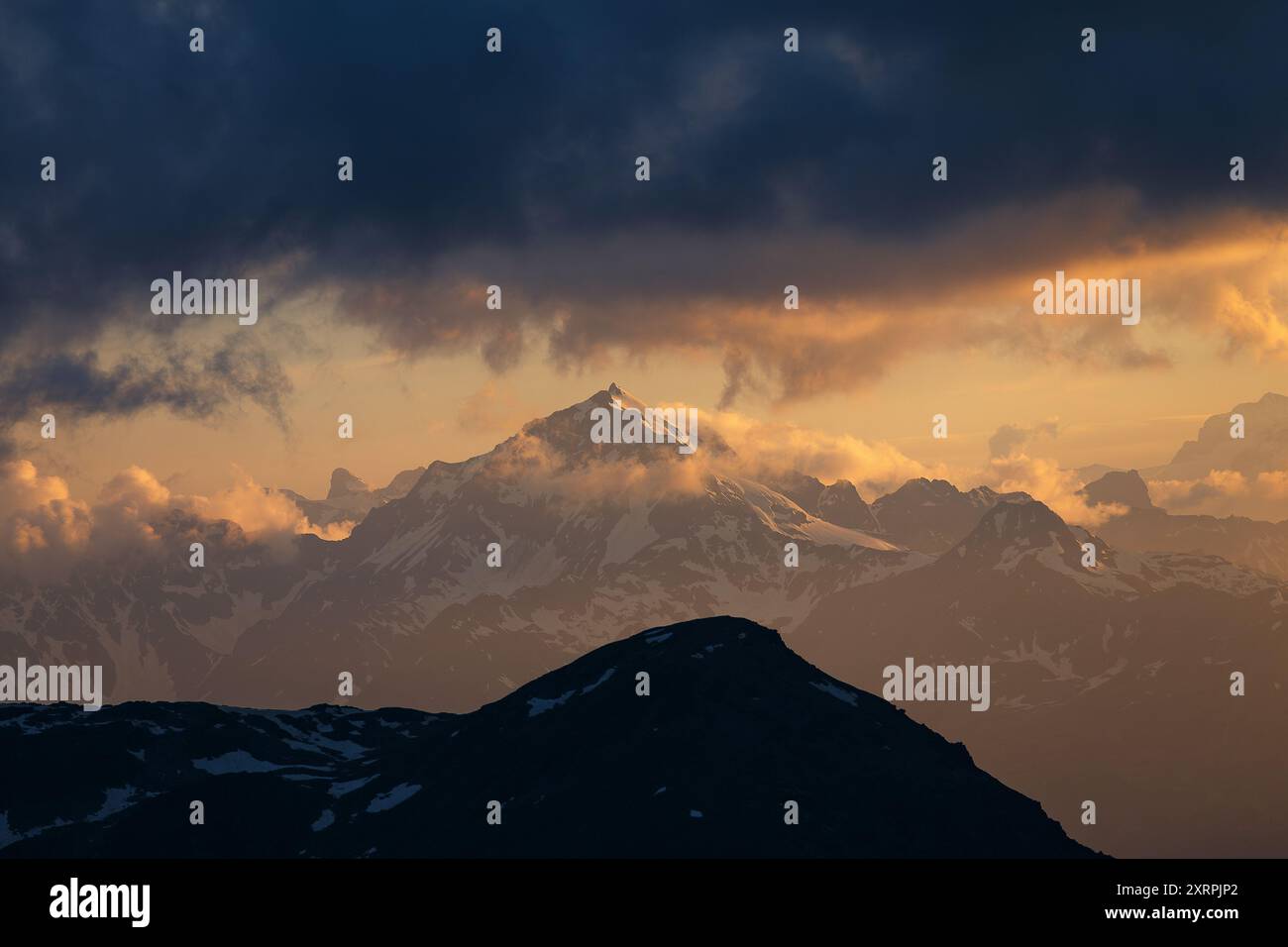 Tramonto emozionante, ombre e luce solare calda sulla cima Piazzi e sulle montagne, cielo spettacolare. Nuvole straordinarie. Alpi. Europa. Foto Stock