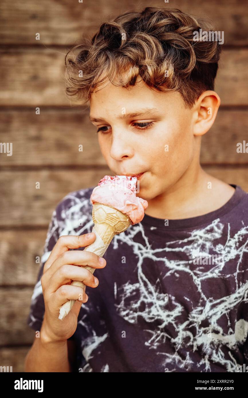 Ragazzo che mangia un delizioso gelato in una giornata calda Foto Stock