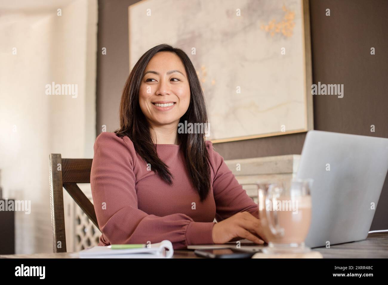 Donna sorridente al computer portatile a casa Foto Stock
