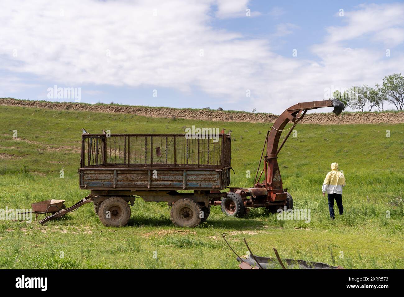 Un uomo cammina in un campo vicino a un vecchio trattore Foto Stock