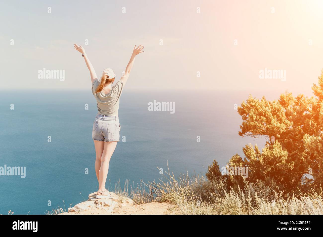 Donna che celebra la vittoria su una scogliera con una vista mozzafiato Foto Stock