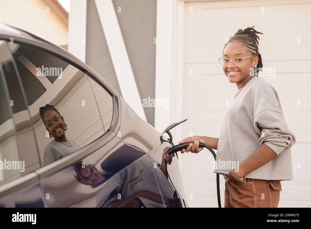 Una ragazza che collega il caricabatterie per auto a casa Foto Stock