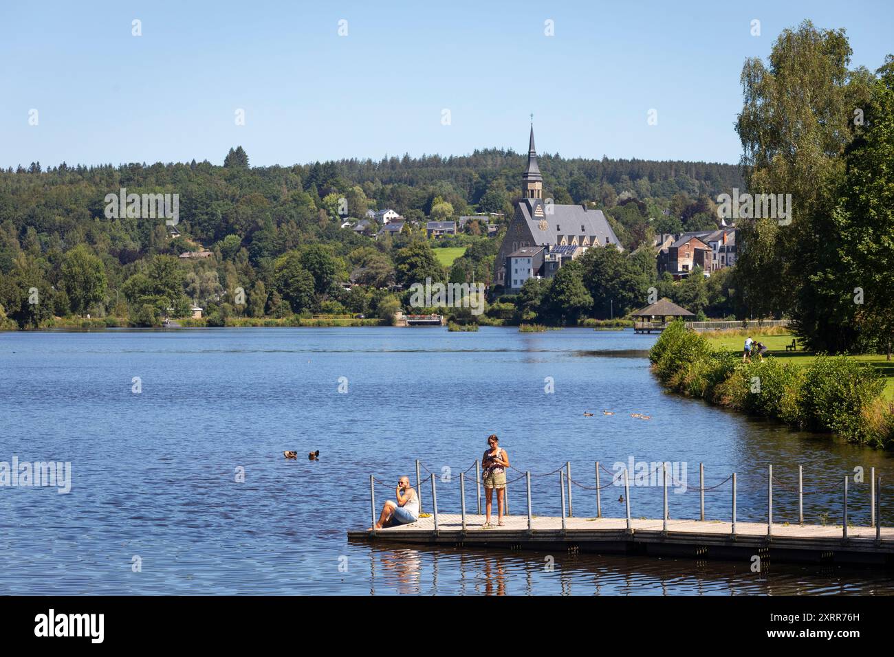 Vista sul villaggio di Vielsalm in estate con persone che si rilassano al lago 'lac des doyards' in primo piano Foto Stock