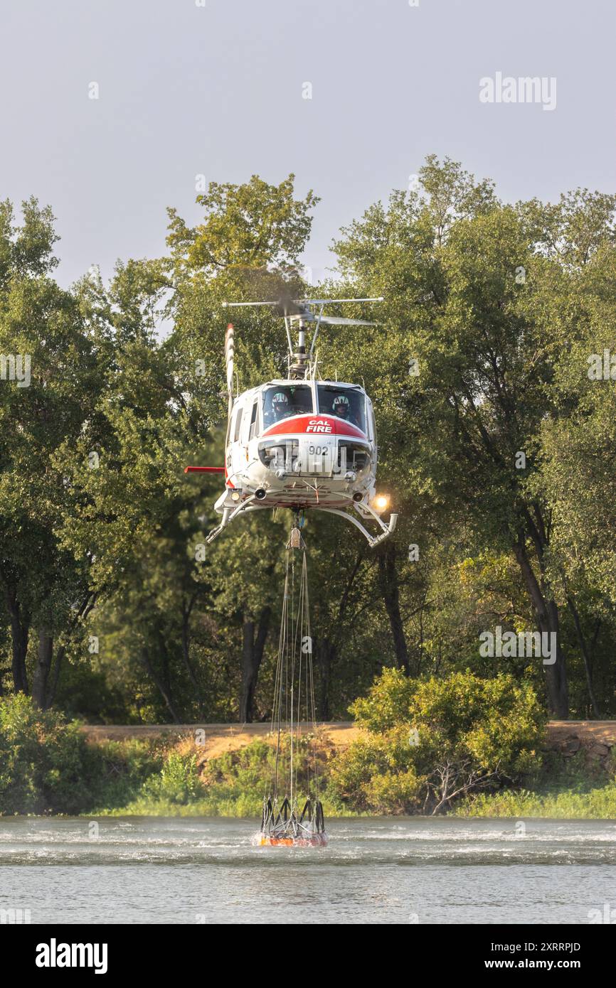 Elicottero Calfire UH-1 che fa uscire l'acqua dal lago Mary a Redding in California per combattere il Lower Fire il 10 agosto 2024. Foto Stock