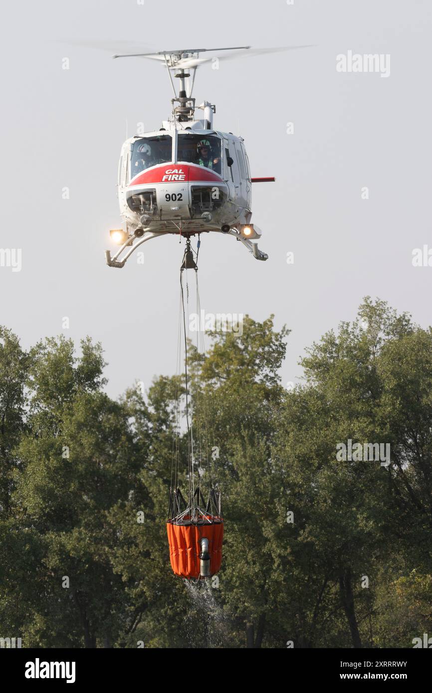 REDDING CALIFORNIA - 10 AGOSTO 2024 - Un elicottero CALFIRE Bell UH-1 decollante con acqua dal lago Mary per combattere il fuoco inferiore vicino a Lower Springs Foto Stock