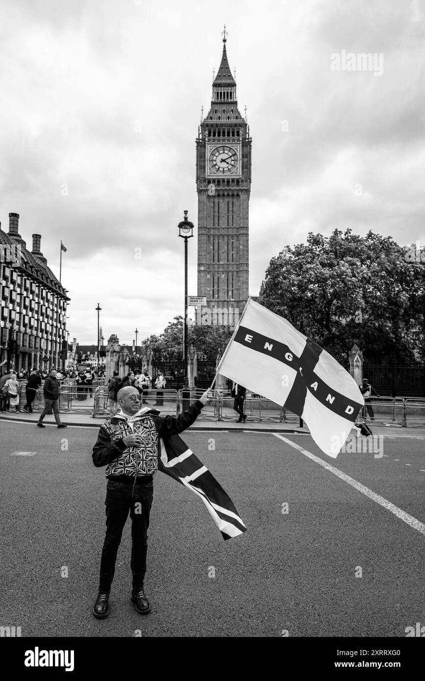 Un uomo che indossa un costume Union Jack inonda una croce inglese della bandiera di San Giorgio fuori dal Big Ben dopo un raduno contro la polizia a due livelli, Londra, Regno Unito. Foto Stock