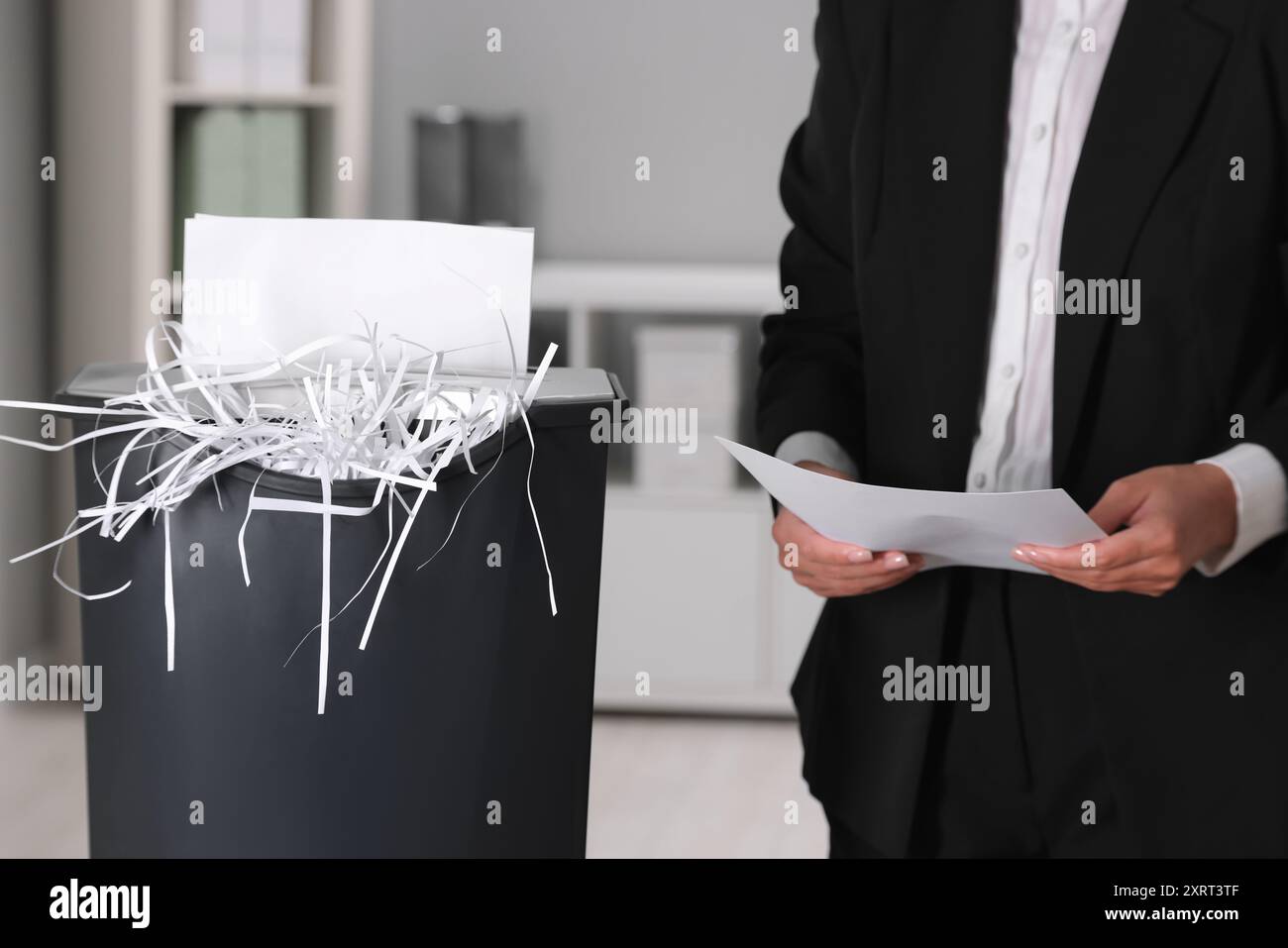 Donna che distrugge fogli di carta con trituratore in ufficio, primo piano Foto Stock