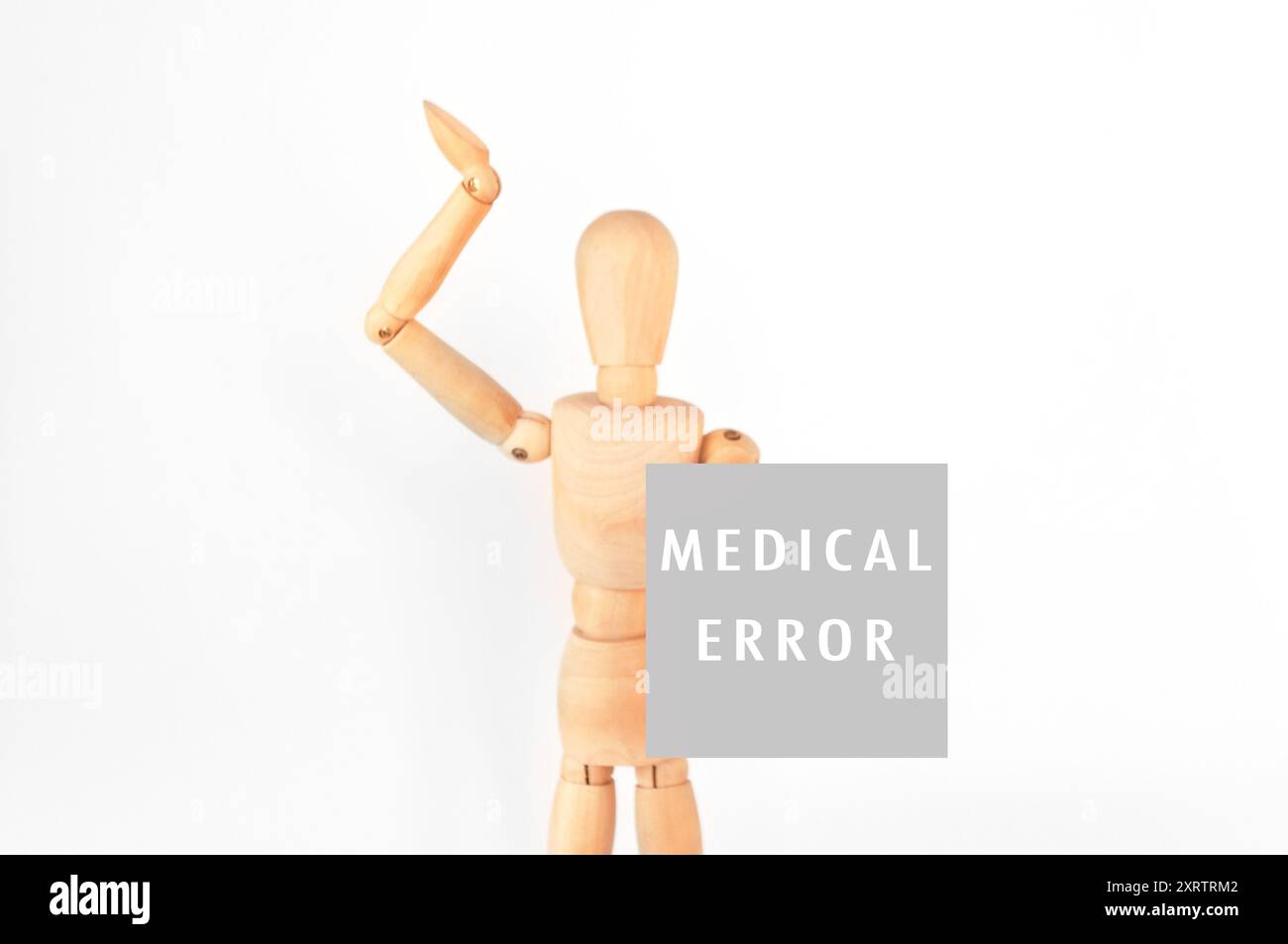Una figura di legno regge un cartello con la scritta errore medico. La figura è in una posa che suggerisce che è in difficoltà o confusione Foto Stock