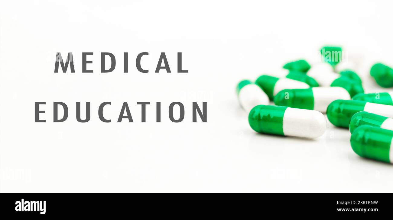 Un mucchio di pillole con le parole educazione medica scritte sotto di loro. Le pillole sono verdi e bianche Foto Stock