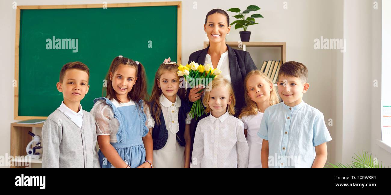 Ritratto di studenti di primo grado con la loro insegnante di classe femminile il primo giorno di scuola. Foto Stock