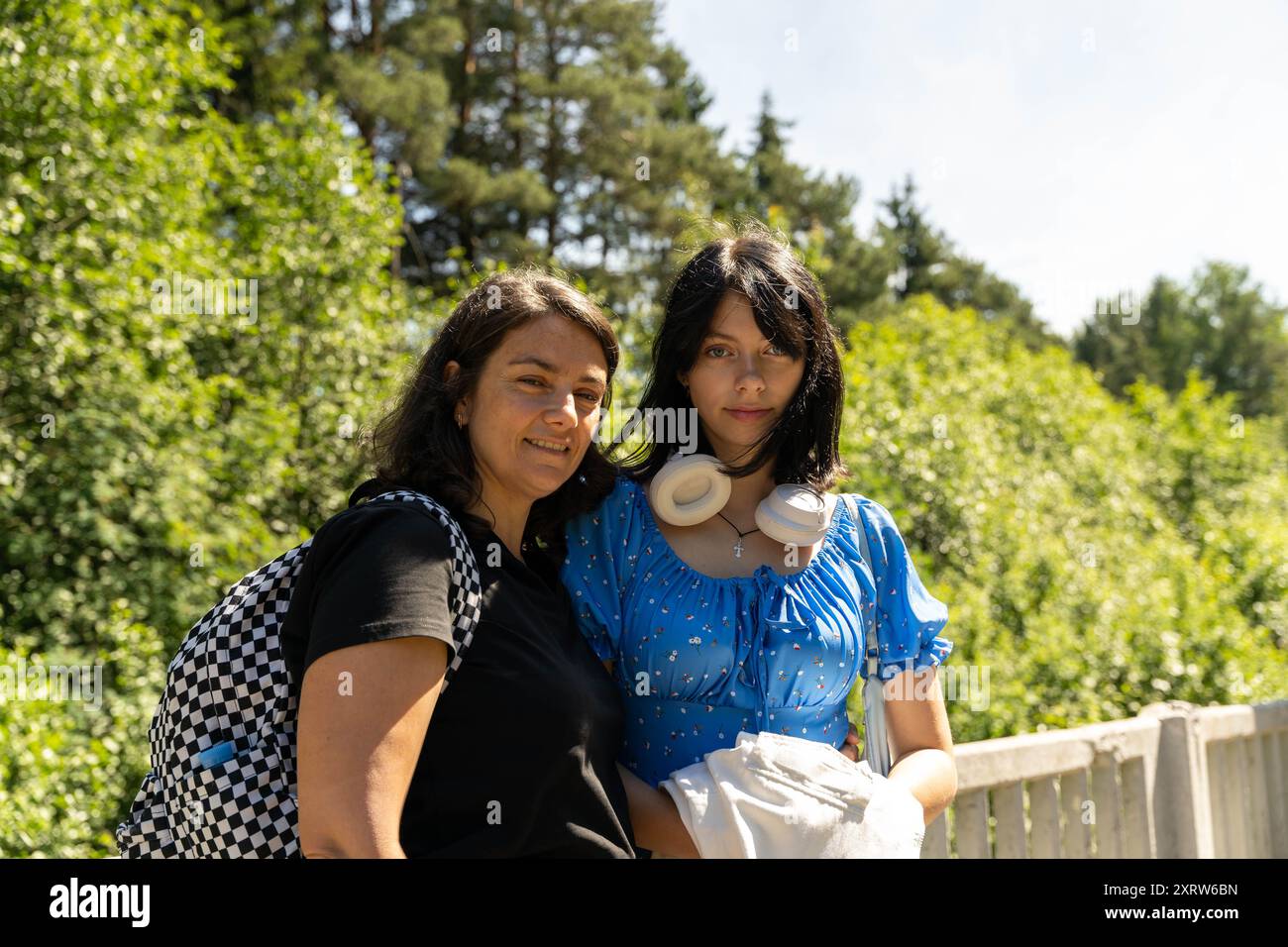 Due donne stanno insieme in un'area boscosa, sorridendo alla telecamera. Foto Stock