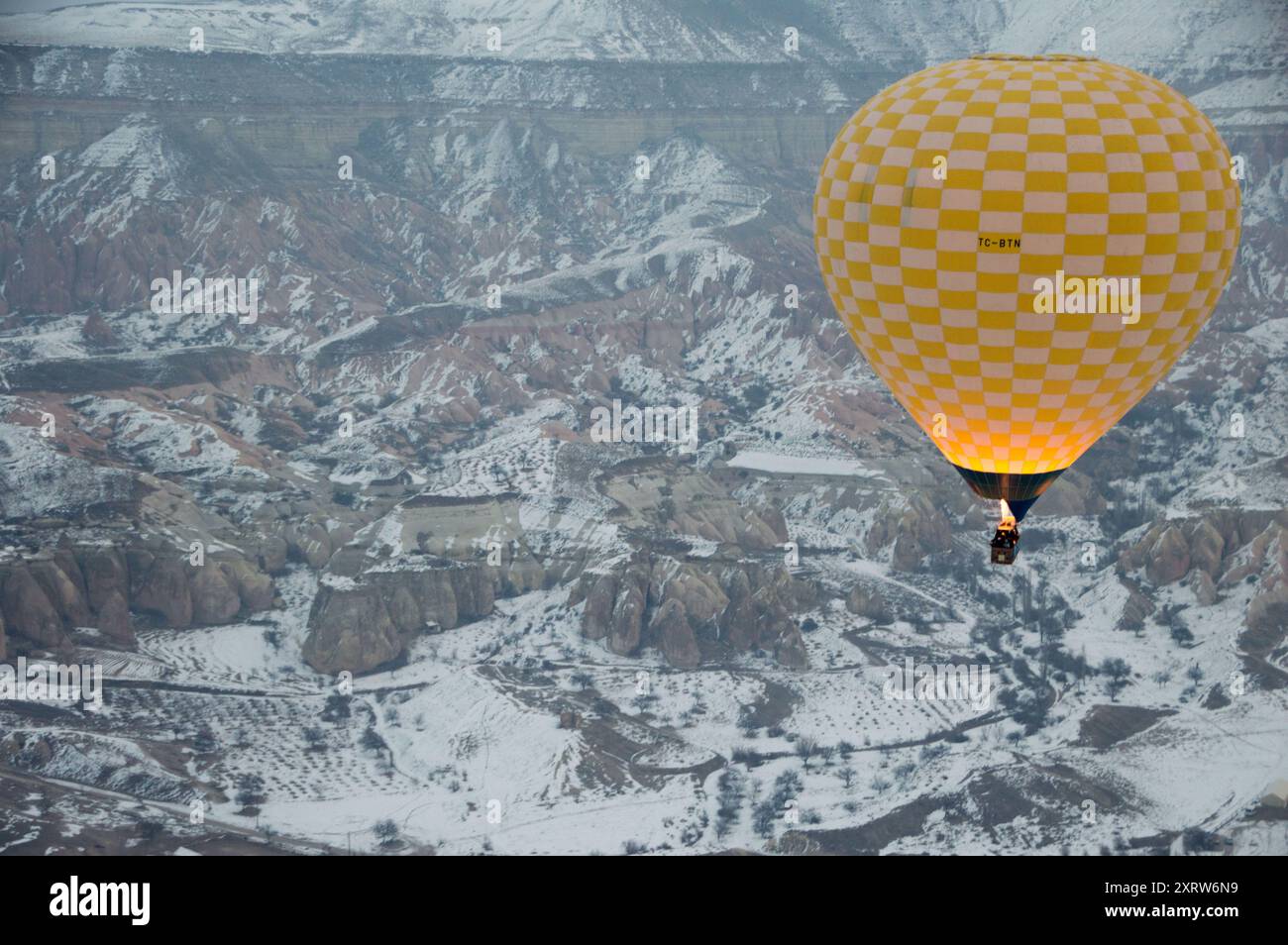 Le mongolfiere sorvolano le valli innevate della Cappadocia all'alba, offrendo paesaggi invernali mozzafiato in questa iconica regione turca. Foto Stock