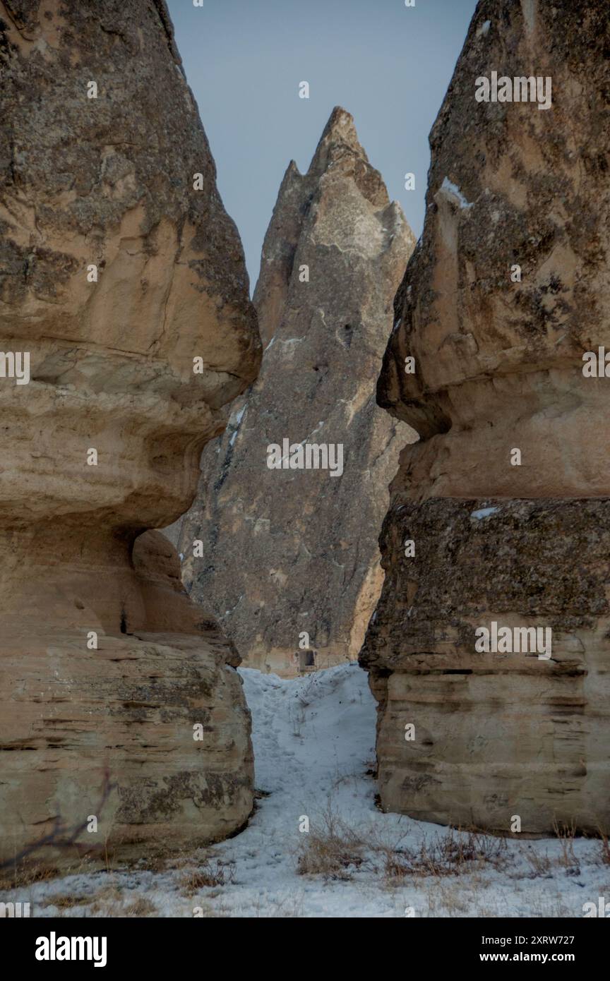 Camini delle fate ricoperti di neve in Cappadocia, Turchia, con antiche abitazioni scavate nelle formazioni rocciose uniche Foto Stock