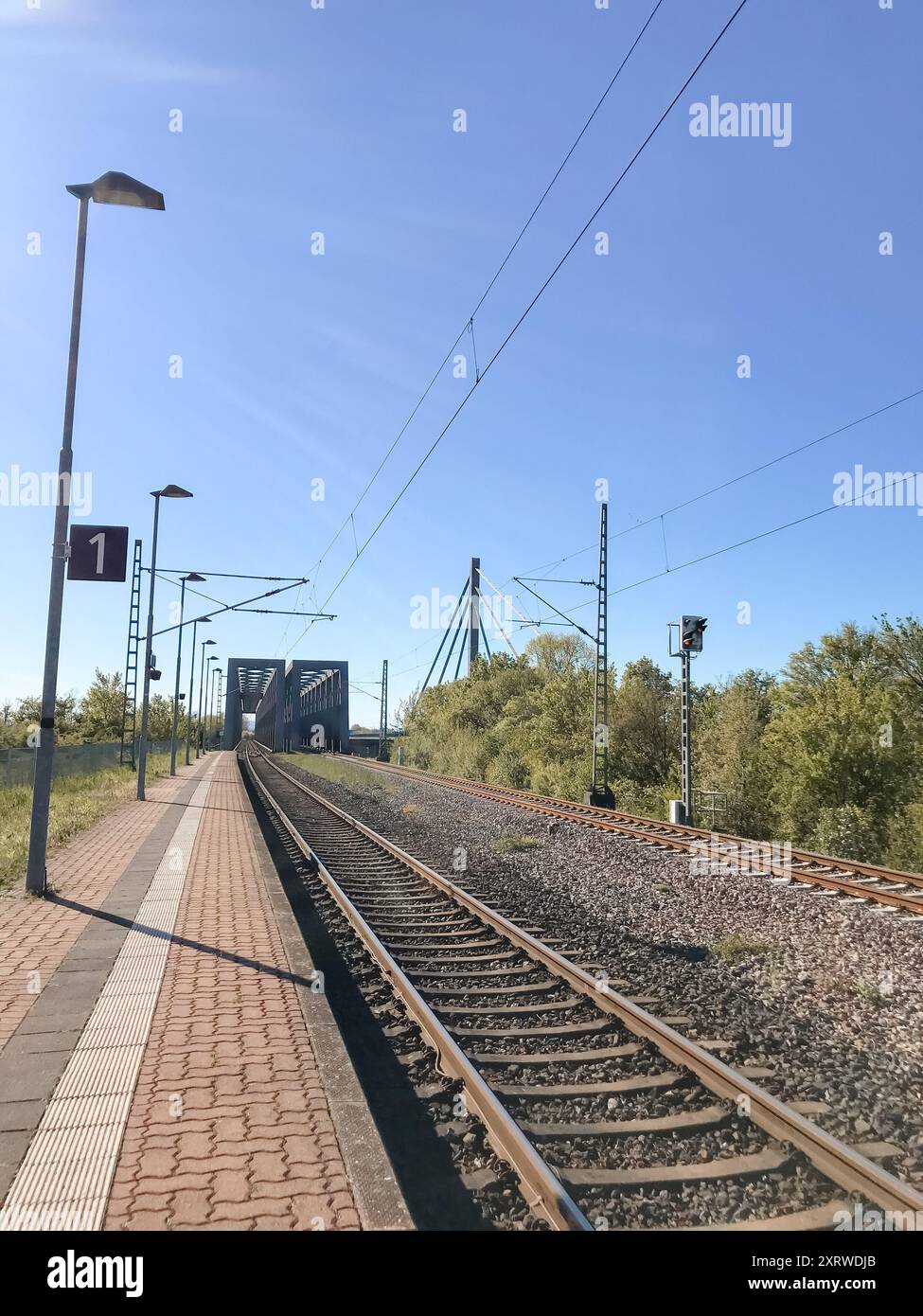 Un binario del treno con un cartello che dice 1. Il cielo è limpido e luminoso. I binari del treno sono vuoti Foto Stock