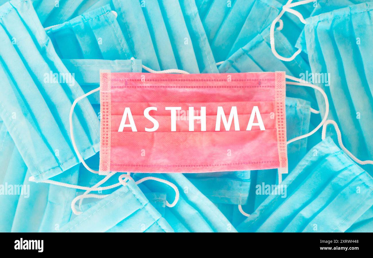 Una maschera blu e rosa con sopra la parola asma. L'immagine ha uno stato d'animo di serietà e cautela, in quanto ricorda di indossare una maschera per proteggire Foto Stock