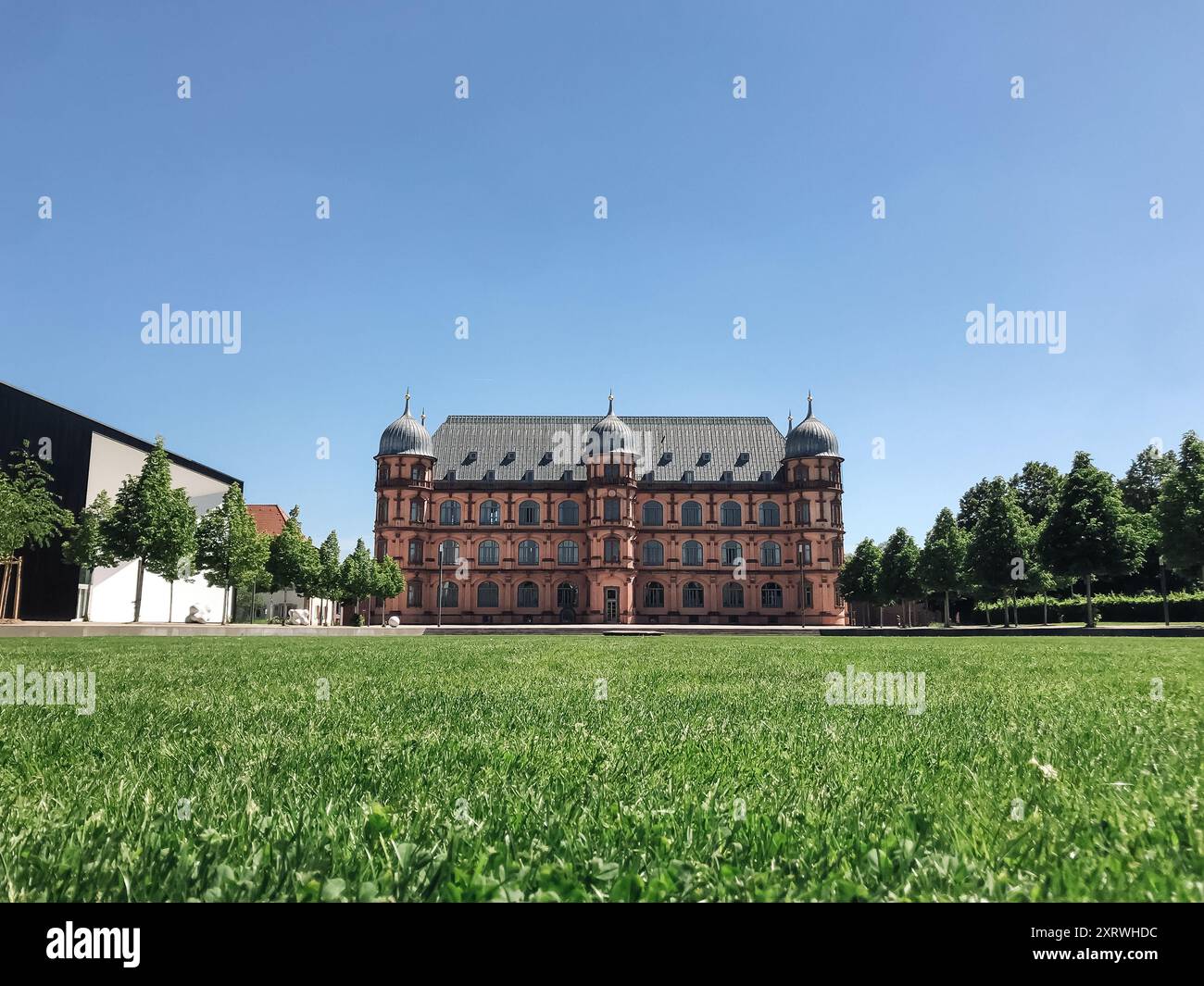 Un grande edificio con un prato verde davanti ad esso. L'edificio è vecchio e ha molte finestre. Il prato è rigoglioso e verde, e il cielo è limpido e. Foto Stock