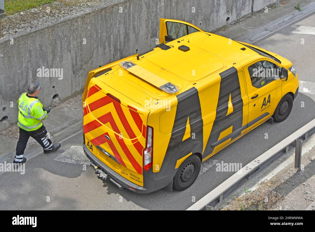 Lo stesso incidente Alamy 2XRWMM1 AA meccanico cammina fino al furgone per trovare gli attrezzi per assistere l'automobilista in un'auto in avaria sotto la copertura del ponte autostradale Essex Inghilterra Regno Unito Foto Stock