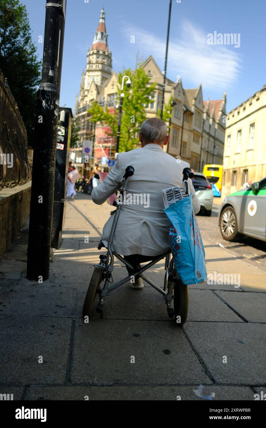 Un uomo anziano in sedia a rotelle in un centro città Foto Stock