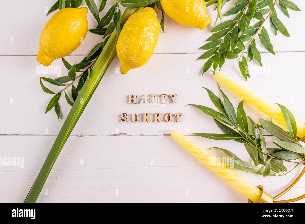 Uno splendido sfondo festivo per la festa del raccolto ebraico di Sukkot con simboli e candele tradizionali. sfondo bianco in legno. Foto Stock