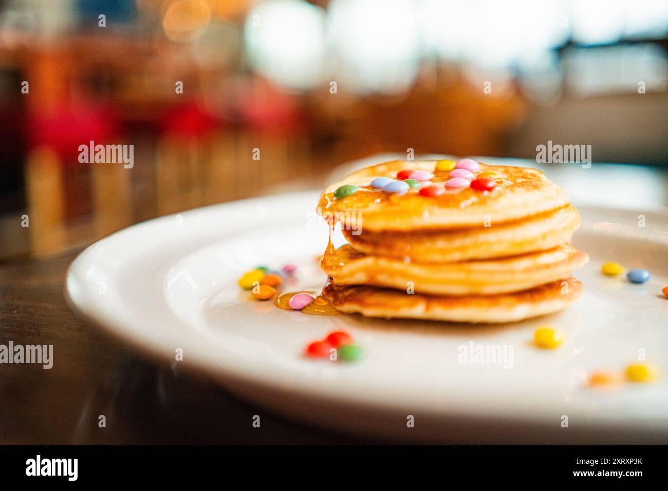 Piccola pila di pancake con miele gocciolante e lenticchie al cioccolato Foto Stock