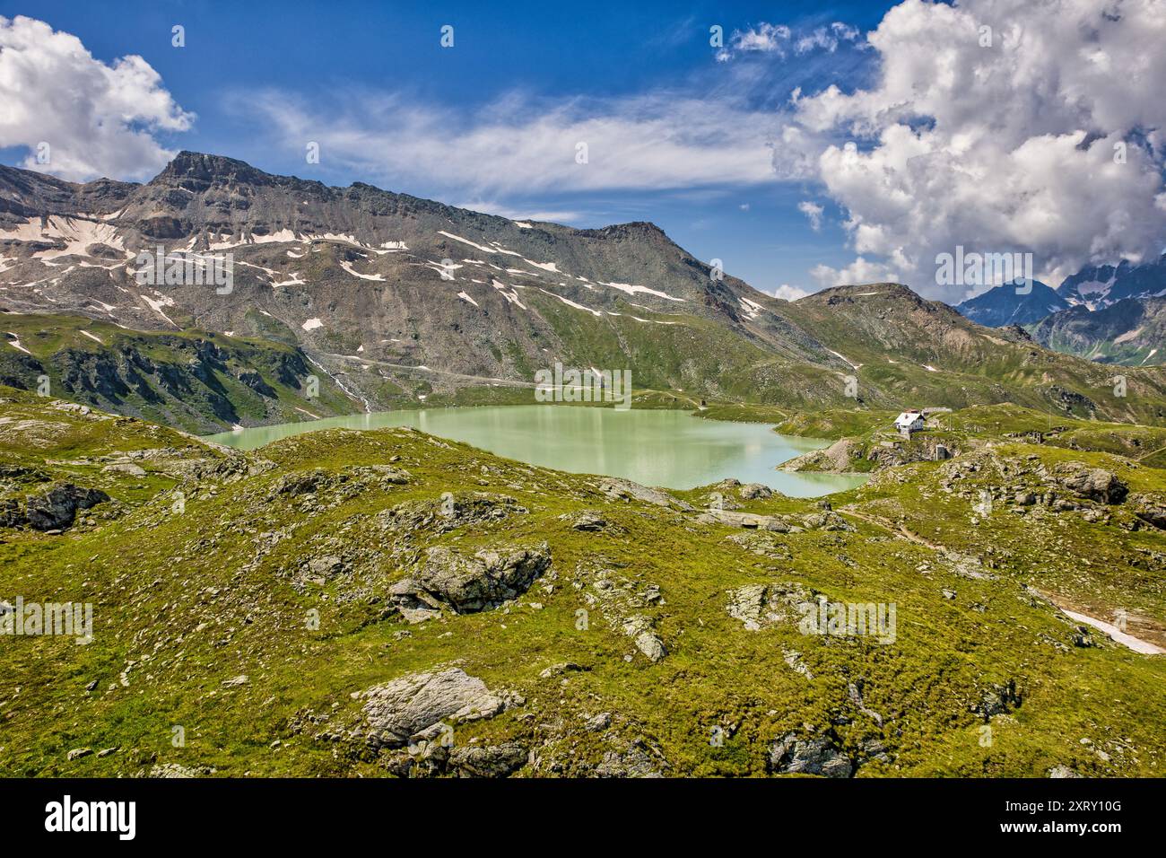 vista dall'alto del verde goillet del lago durante il sole estivo con le alpi sullo sfondo sotto un cielo blu con alcune belle nuvole Foto Stock