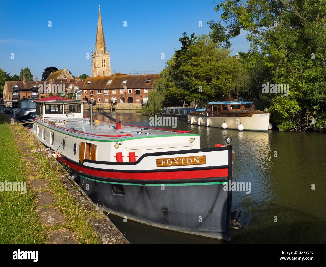 Case galleggianti ormeggiate sul Tamigi ad Abingdon. Una bella vista del Tamigi ad Abingdon, nelle prime ore di una mattina d'estate. Siamo sulla riva sud del fiume, guardando dall'altra parte verso la chiesa anglosassone di Sant'Elena da cui prende il nome il molo. Foto Stock